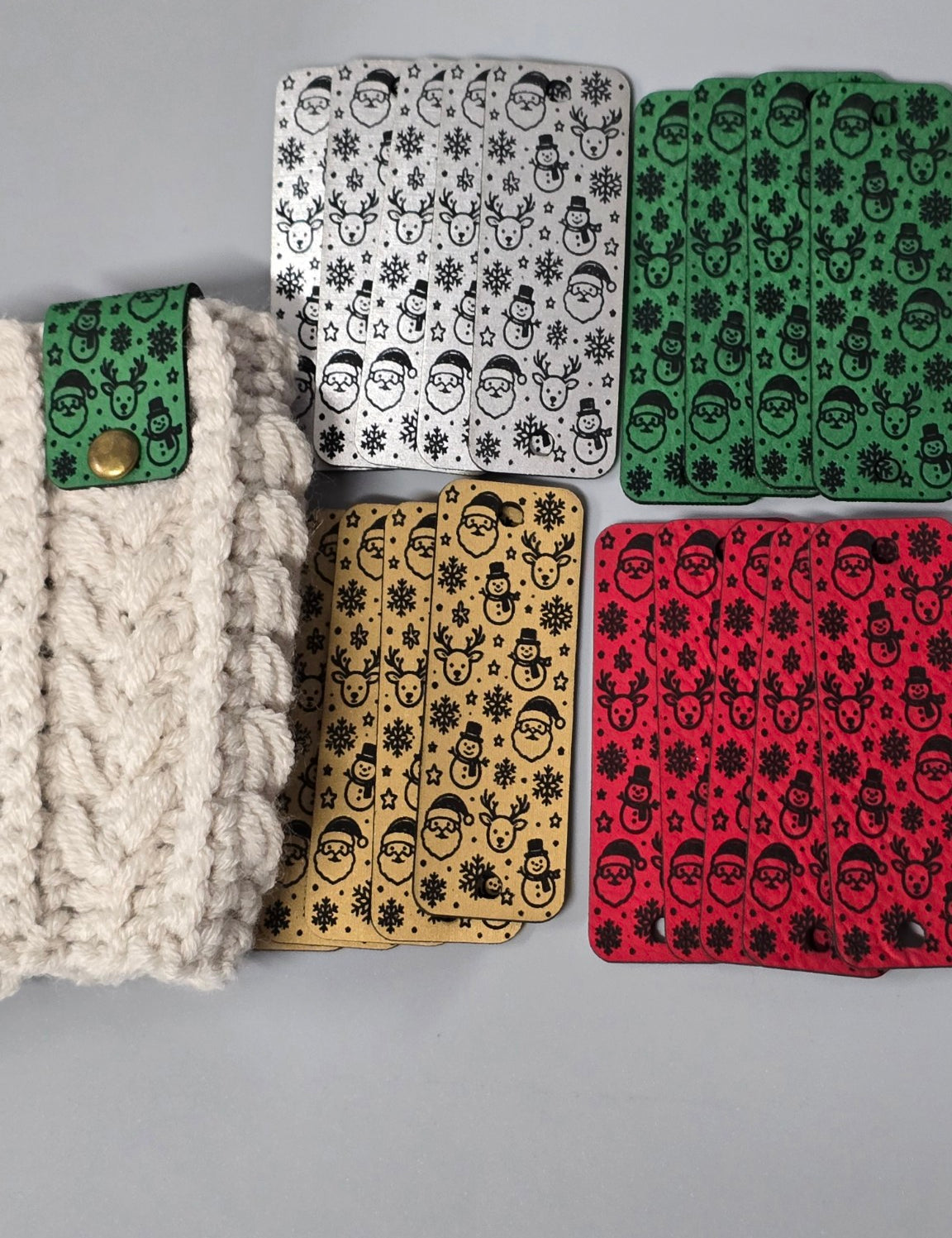 Christmas fold-over tags in four colors beside a green tag attached to cream crochet fabric.
