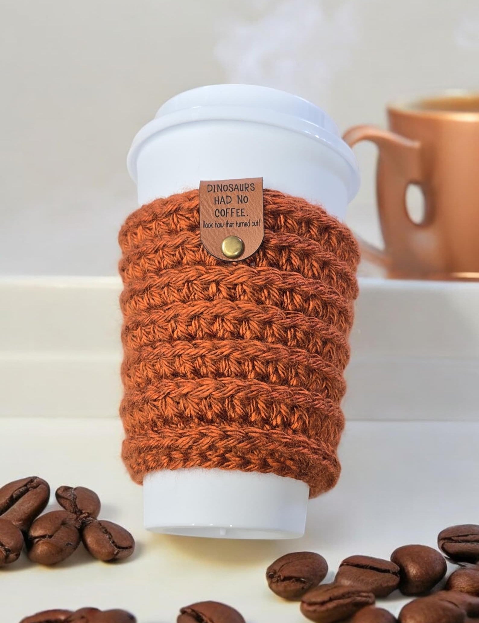 Dinosaurs had no coffee tag attached to a rust crochet cup cozy
