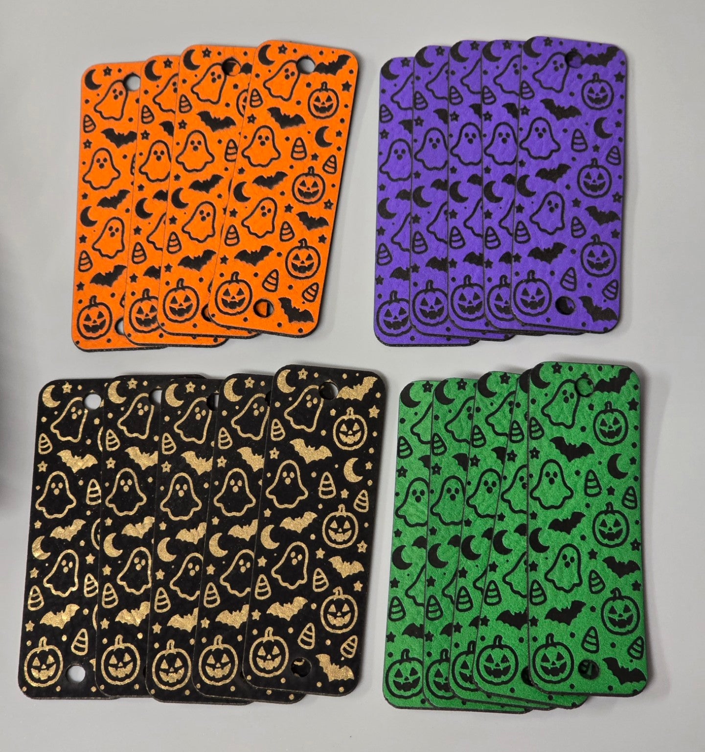 Halloween fold-over tags in orange, purple, black, and green, with pumpkins, ghosts, bats, crescent moons, stars, and candy corn. Black tags feature gold engraving.
